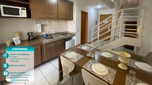 Een moderne keuken met inbouwapparatuur, een eethoek met een tafel gedekt voor vier personen, en een interne trap.