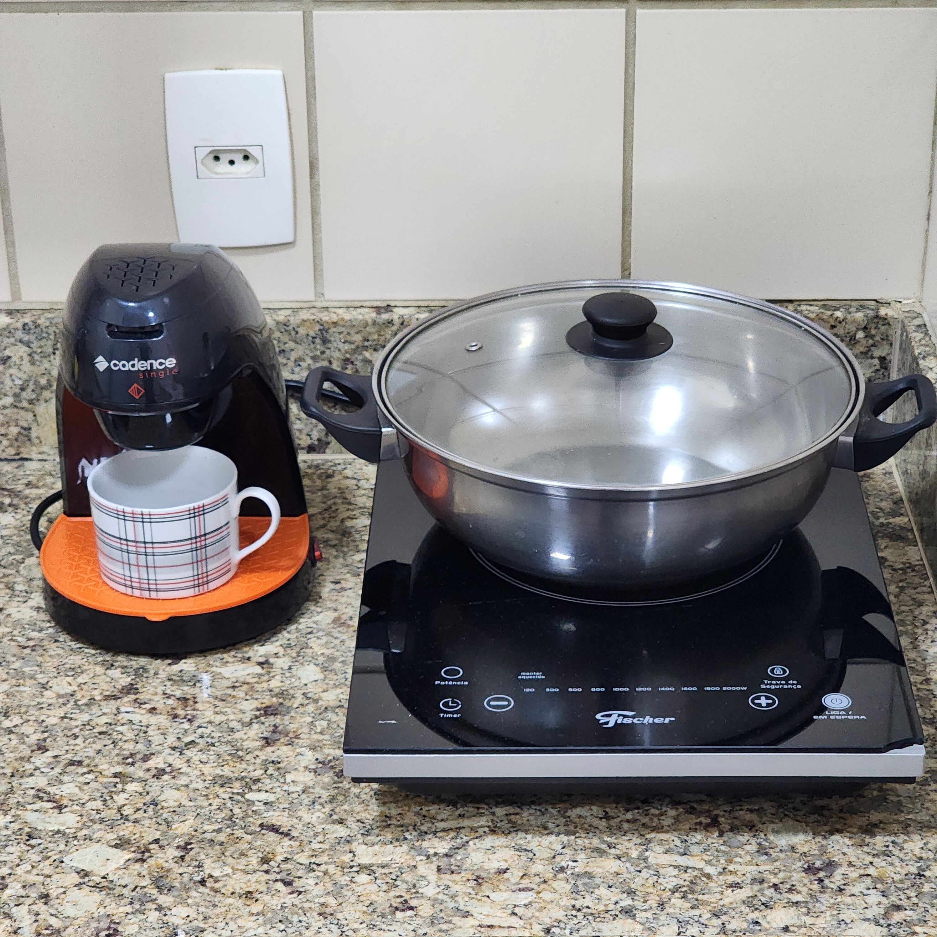 A kitchen with a stove top cooker, a coffee maker, and a mug on a countertop.