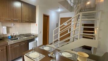 A modern kitchen with integrated appliances, a dining area with a table set for four, and an internal staircase.