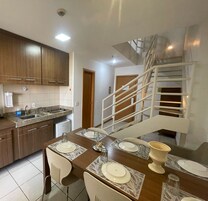 Una cocina moderna con electrodomésticos integrados, un comedor con mesa dispuesta para cuatro personas y una escalera interior.