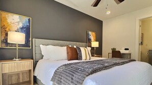 Ein modernes Schlafzimmer mit einem großen Bett, zwei Nachttischen und einem Deckenventilator.