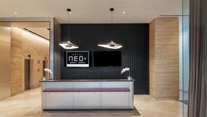 Una moderna zona de recepción de hotel con pantalla digital, mobiliario elegante y un diseño minimalista.