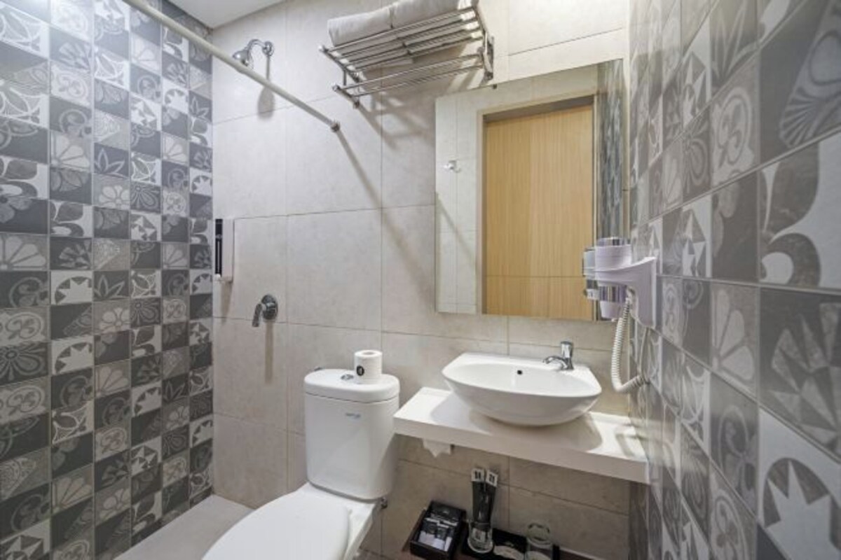 A bathroom with patterned tiles, a toilet, a sink, and a shower.