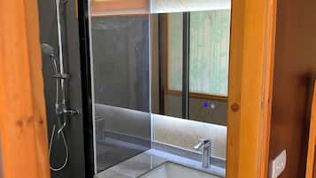 A modern bathroom with a glass-enclosed shower, a sink, and a towel rack.