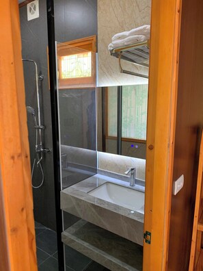 A modern bathroom with a glass-enclosed shower, a sink, and a towel rack. - Ngan Nga Legend (Bac Ha)