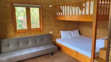 Una habitación con literas, un sofá y una ventana que da a zonas verdes.