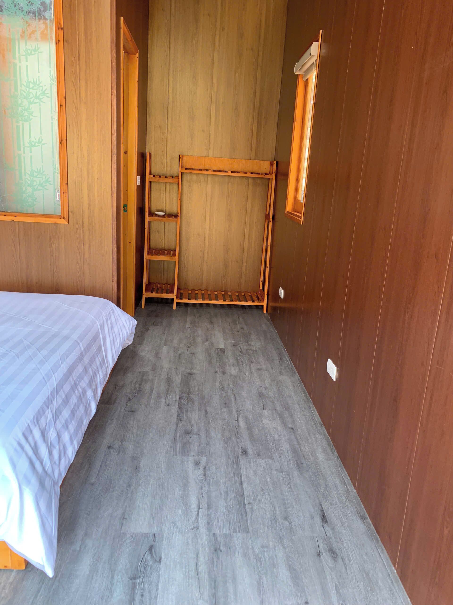 A room with a bed, a wooden ladder, and a window.
