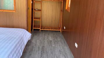 A room with a bed, a wooden ladder, and a window.