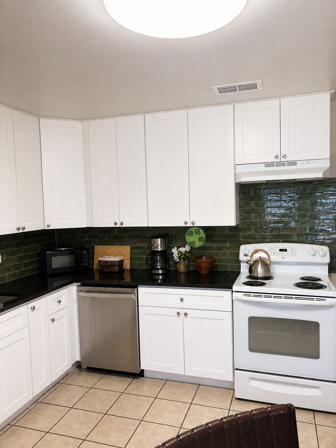 A kitchen with white cabinets, a microwave, a coffee maker, and a stove.