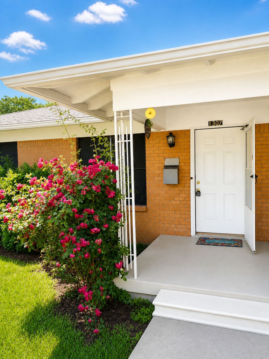 A residential building with a white door, a mailbox, and a small porch with a light fixture.