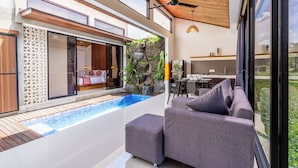 A modern outdoor living area with a pool, grey sofas, and a dining area. - Eden Villas Ubud (Ubud)