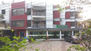 A multi-story hotel with a red and white facade, balconies, and a sign for Hotel Garden City.
