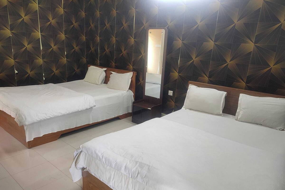 A hotel room with two single beds, a large mirror, and a geometric patterned wall.