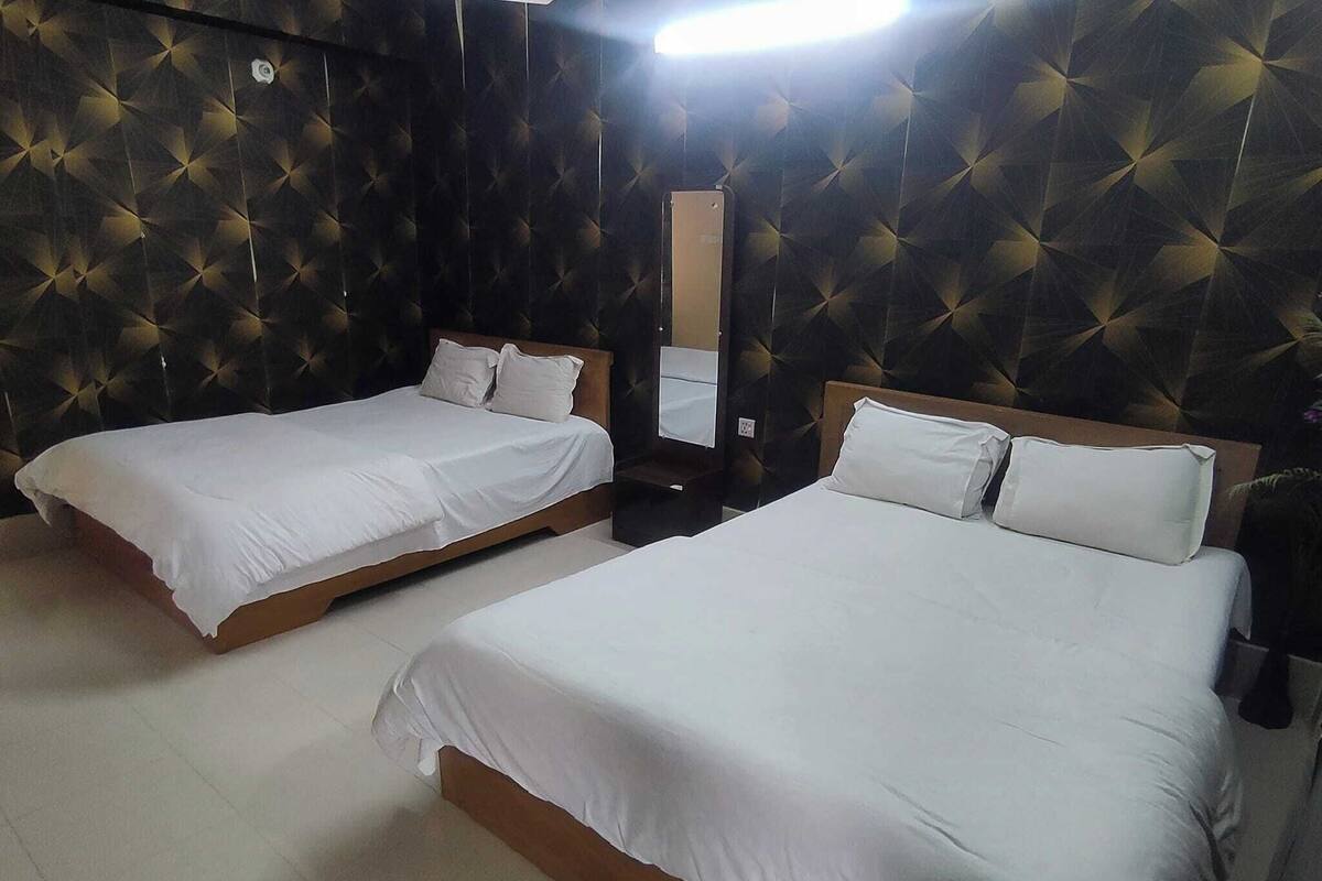 A hotel room with two beds, each with white bedding and wooden headboards.
