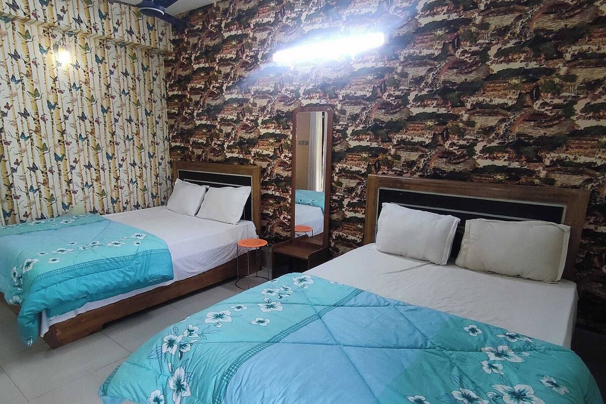 A room with two beds, a mirror, and a patterned wall.