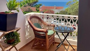 A balcony with a wicker chair, a small table, and potted plants. - SUITE CON VISTAS A PLAYA DE SON BOU (Son Bou (Platja))