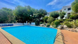 A swimming pool with a clear blue water, surrounded by a brick walkway and lush greenery. - SUITE CON VISTAS A PLAYA DE SON BOU (Son Bou (Platja))