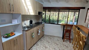 A kitchen with wooden cabinets, a gas stove, a sink, and a dining area with wooden chairs. - VILLA LIGIA IN MEDELLIN (Medellín)
