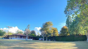 A spacious outdoor area with a covered seating area, a car, and a hedge. - VILLA LIGIA IN MEDELLIN (Medellín)