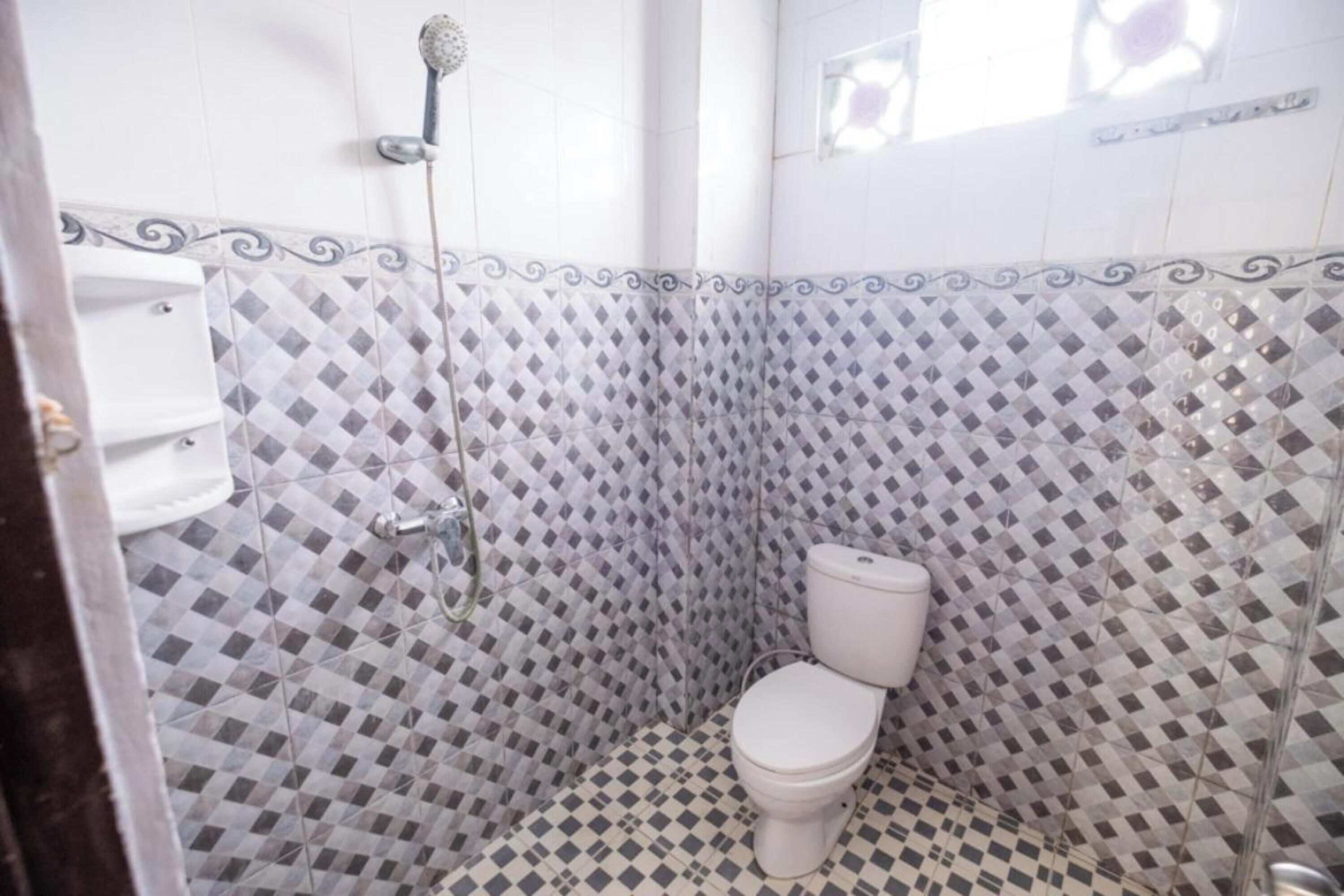 Un baño con piso de baldosas a cuadros, un inodoro y una ducha.