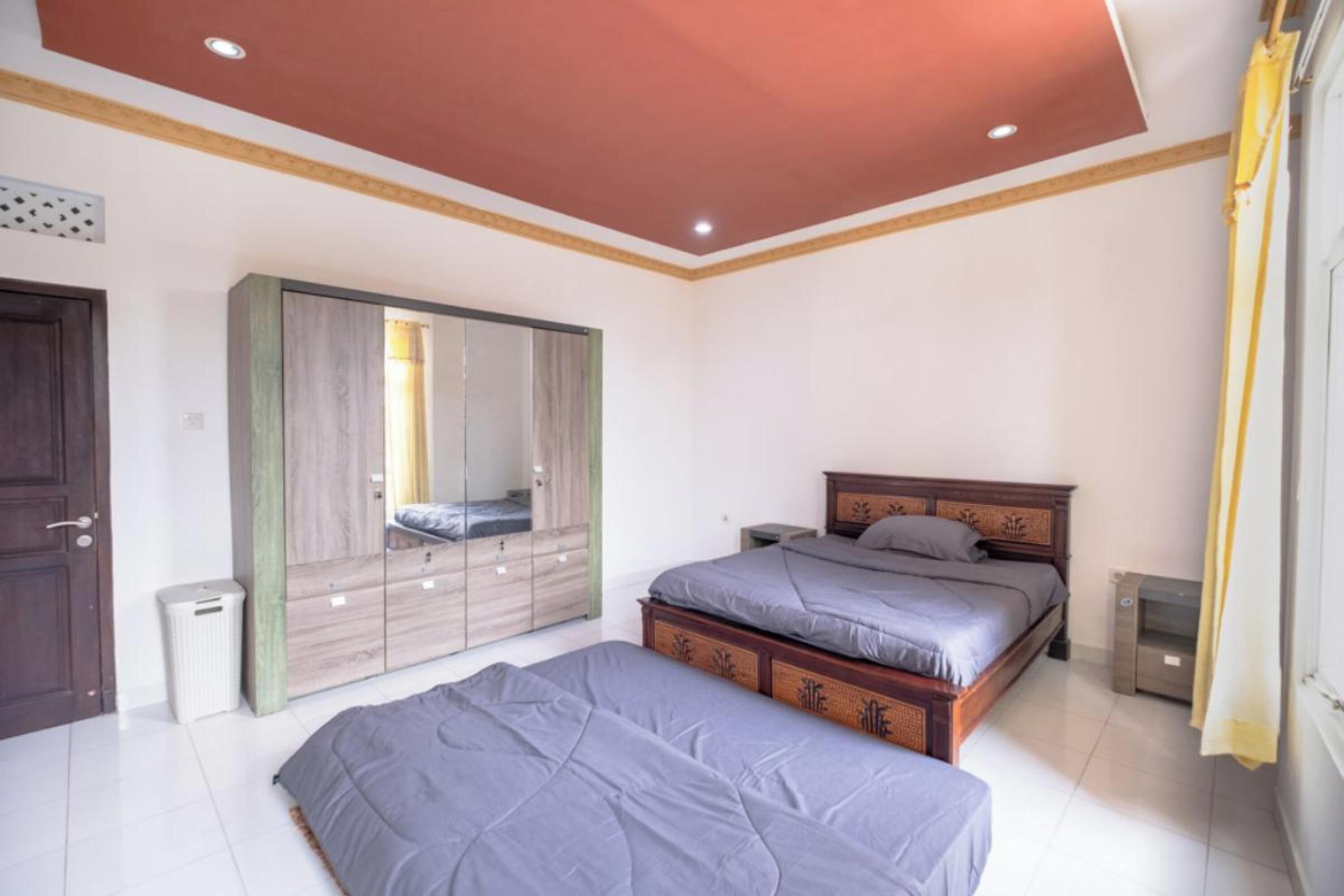 A bedroom with a large wardrobe, two beds, and a ceiling light.