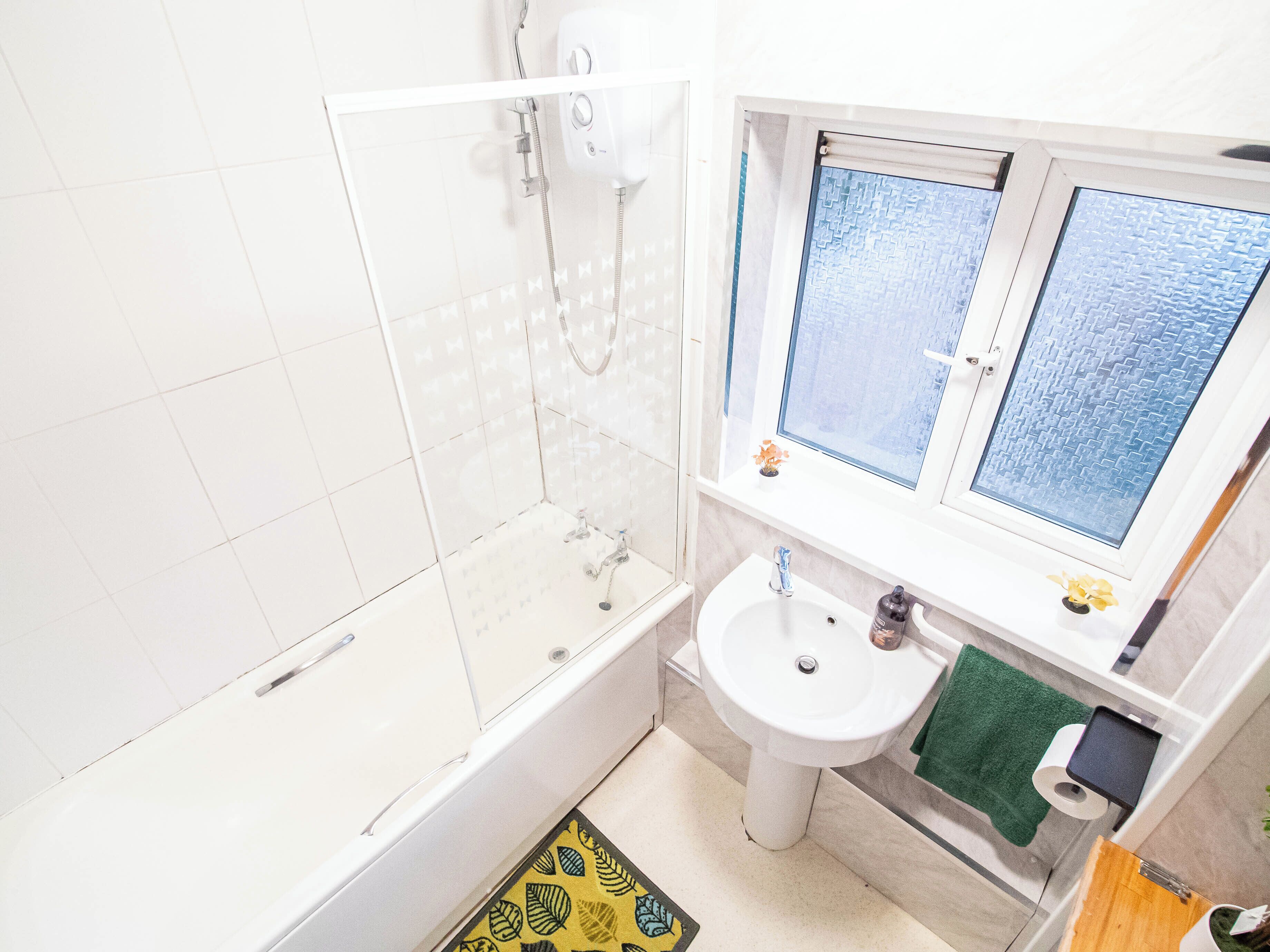 Une salle de bain avec une baignoire, un lavabo et une fenêtre.