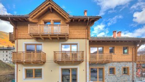 A two-story wooden building with balconies, large windows, and a stone facade. - Arnica Ski In 10 m, Livigno, Italy (Livigno)