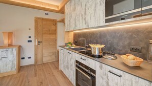 A modern kitchen with a built-in microwave, oven, and sink. There is a wooden door and a cabinet with drawers. - Arnica Ski In 10 m, Livigno, Italy (Livigno)