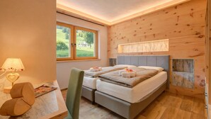 A bedroom with a bed, a desk with a lamp, a chair, and a window with a view of greenery. - Arnica Ski In 10 m, Livigno, Italy (Livigno)