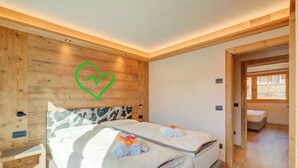 Ett hotellrum med två sängar, sänggavlar i trä, en hjärtformad väggdekoration och ett litet nattduksbord.