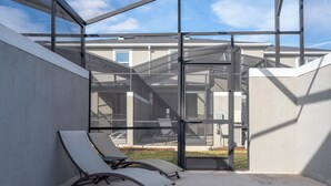 A glass-enclosed outdoor area with two lounge chairs and a pool. - 4337 QS - Charming Hideaway (Kissimmee)