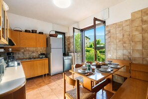 Une cuisine avec des meubles en bois, un réfrigérateur en acier inoxydable et une table à manger pour quatre personnes.
