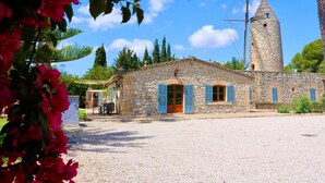 Un bâtiment en pierre doté d’une tour, une cour recouverte de gravier et un petit espace extérieur aménagé avec des sièges.