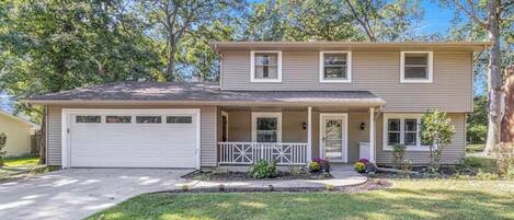 A two-story house with a garage, a front porch, and a well-maintained lawn.
