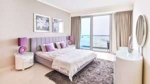 A modern bedroom with a large bed, two bedside tables with lamps, a dresser, and a balcony view.