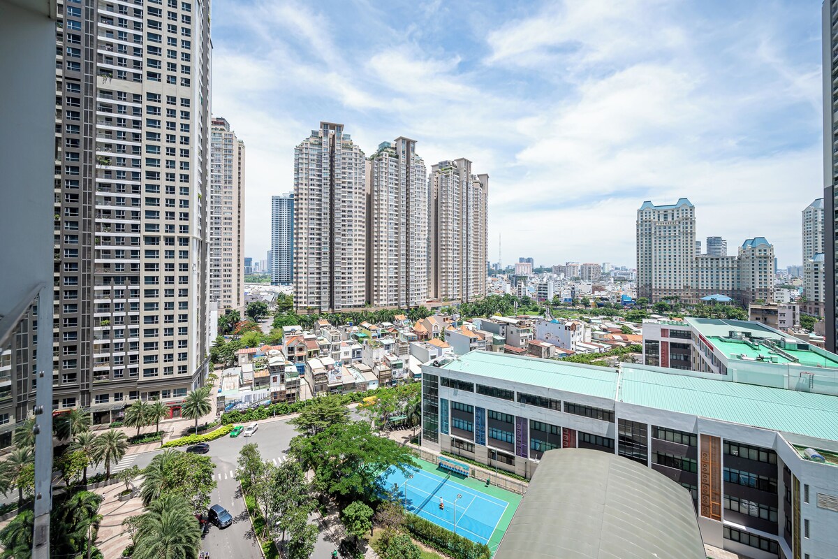Un edificio residencial de gran altura con varios pisos, un patio central con cancha de tenis y edificios más pequeños alrededor.