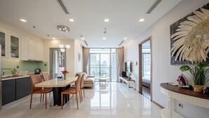 A modern kitchen with a dining area, a sofa, and a TV. - Vinhomes Central Park Apartment by Hava (Ho Chi Minh City)