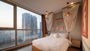 A bedroom with a large window, a bed, a bedside table, and a wall-mounted lamp. - Vinhomes Central Park Apartment by Hava (Ho Chi Minh City)