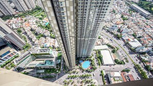 A high-rise building with a pool surrounded by greenery and a parking area. - Vinhomes Central Park Apartment by Hava (Ho Chi Minh City)