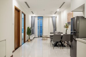 A modern kitchen with a refrigerator, dining table, and chairs.