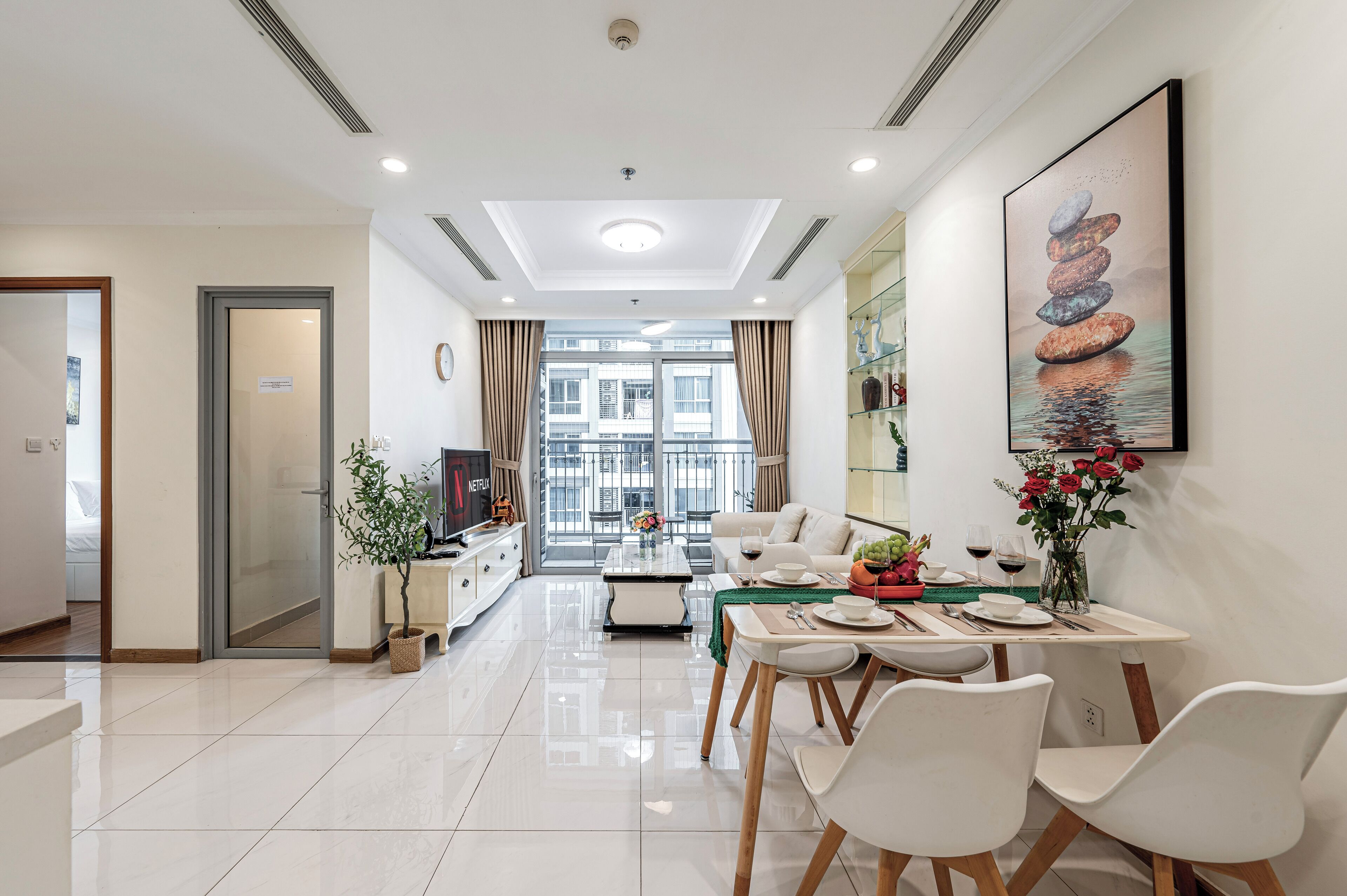 A modern living room with a dining area, a large window, and a view of the city.