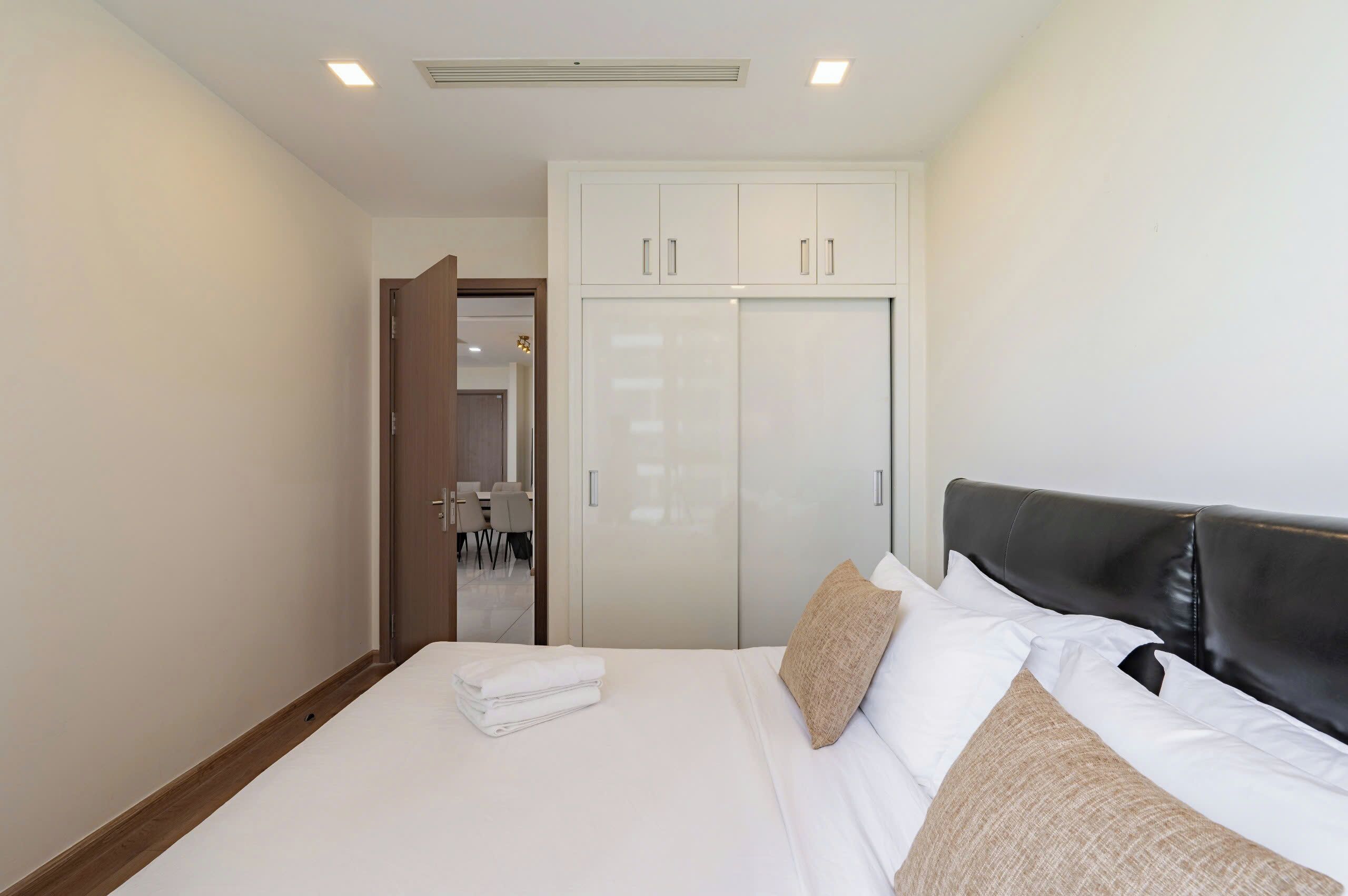 A bedroom with a bed, pillows, a wardrobe, and a door leading to a bathroom.