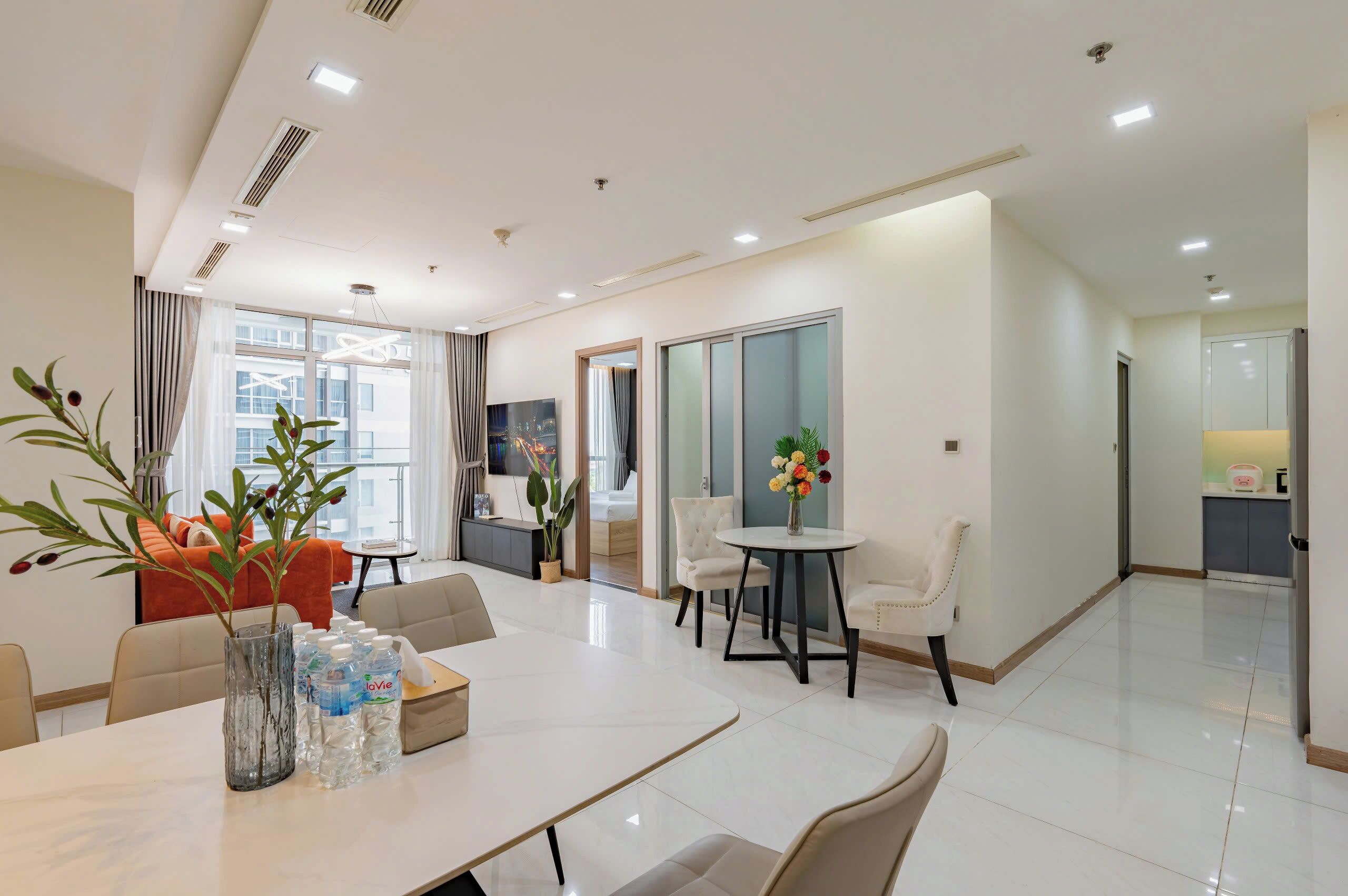 A modern hotel room with a dining area, a kitchen, and a living space.