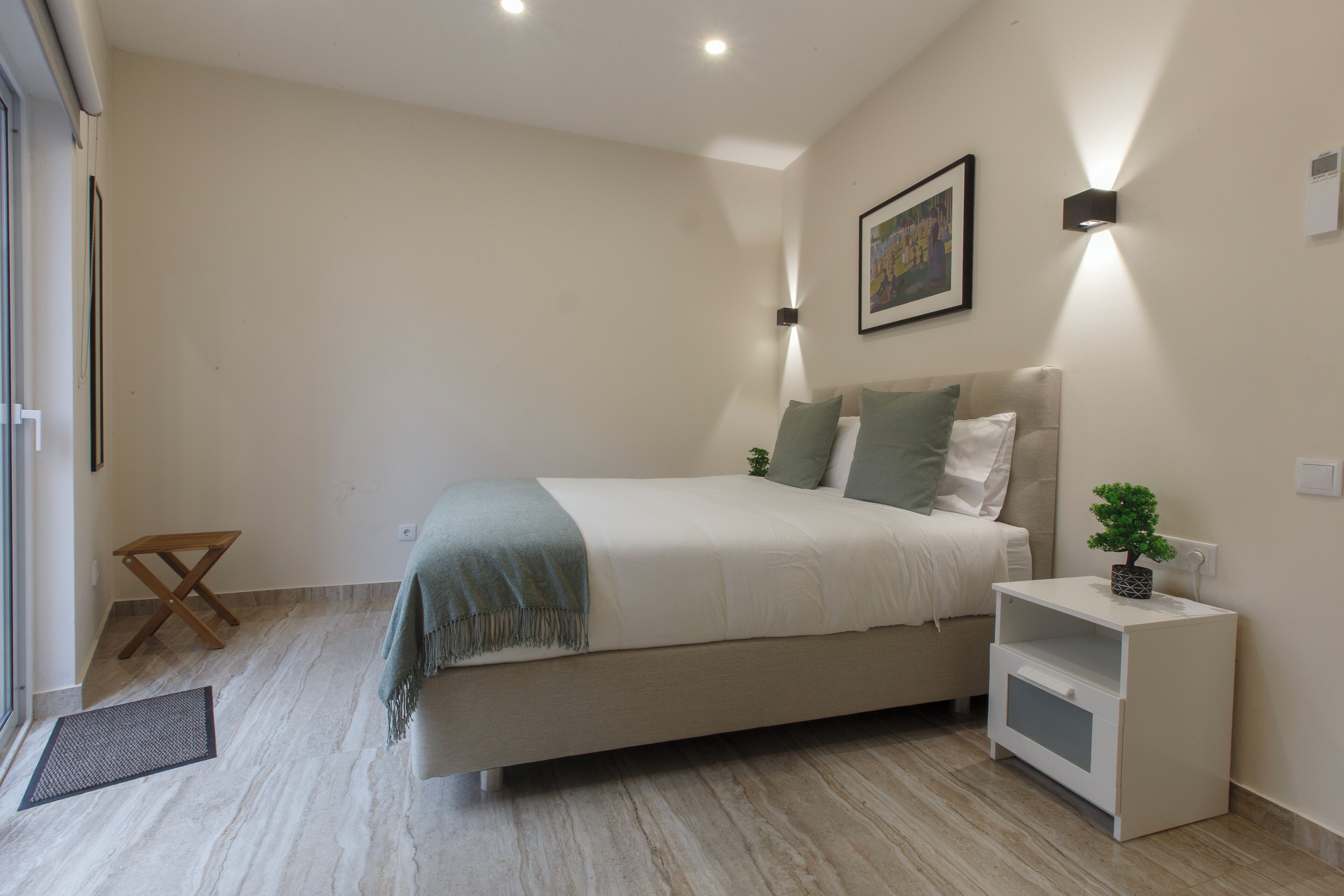 Un dormitorio con cama, mesita de noche y una pequeña planta.