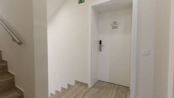 Un couloir au sol en marbre menant à une porte portant l’inscription « 201 ».