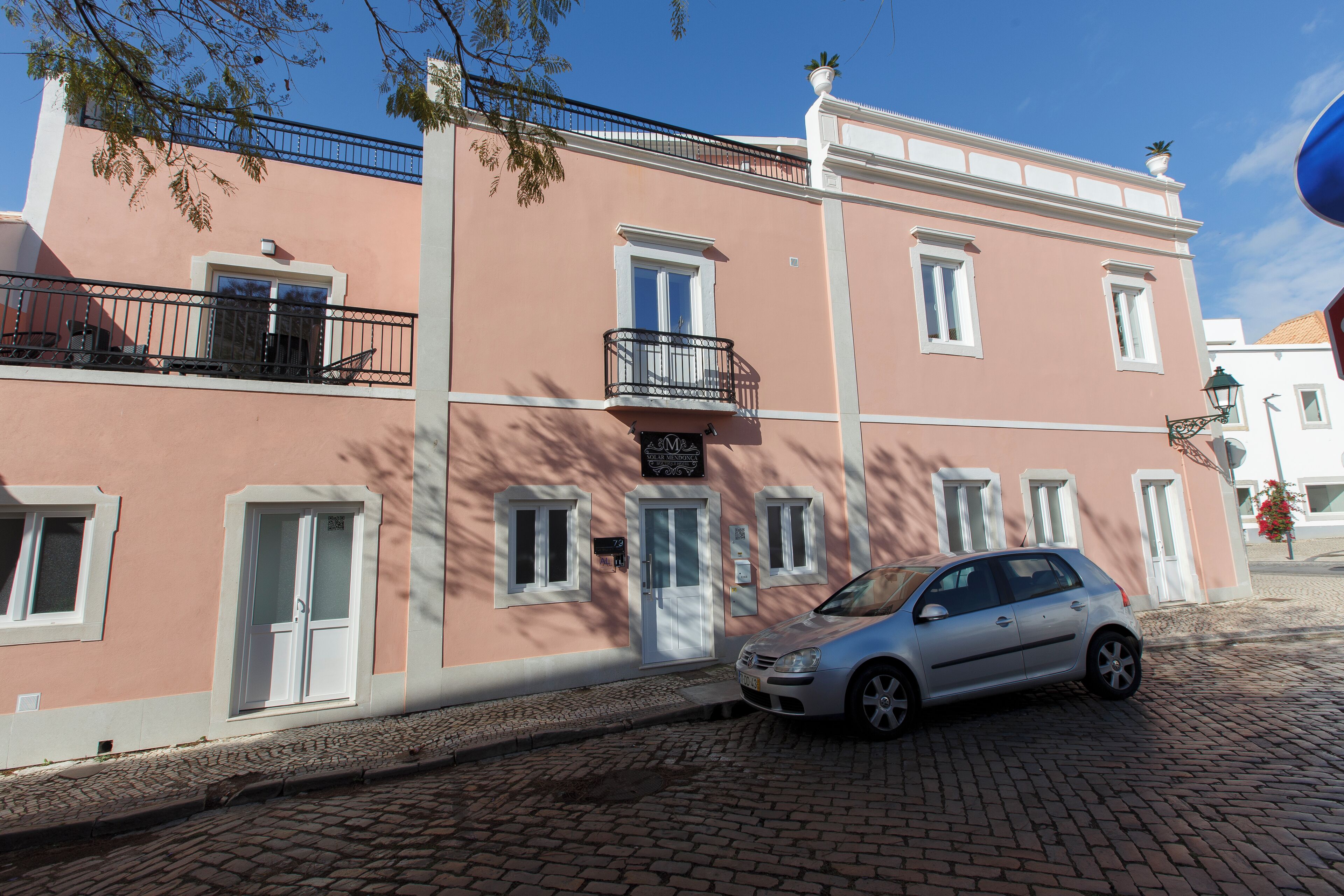 Un bâtiment rose avec une voiture garée devant.