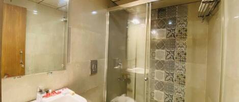 A modern bathroom with a glass-enclosed shower, a white sink, and a toilet.