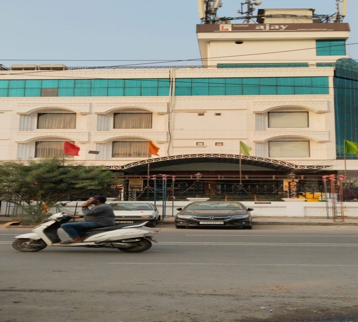 Un hotel con fachada moderna, un acceso cubierto y una bandera al frente.