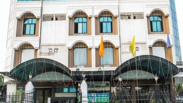 A multi-story building with a classical facade, featuring arched windows and a central entrance with a canopy. - Hotel Ajay International (Prayagraj)