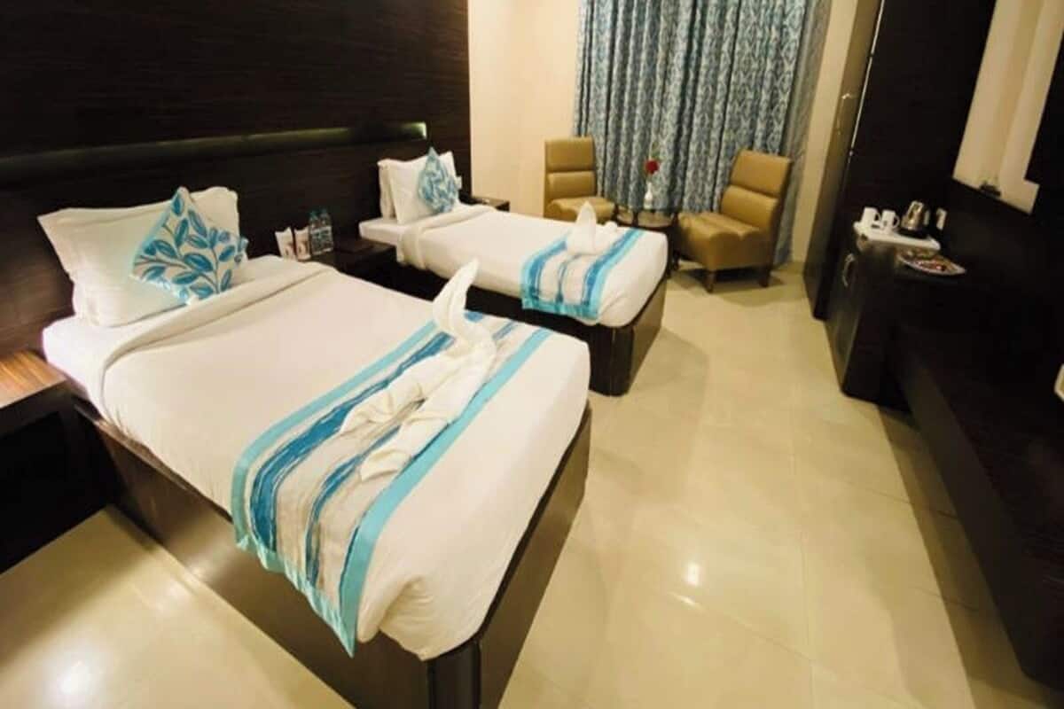 Une chambre d’hôtel avec deux lits, un canapé, une chaise et une petite table.